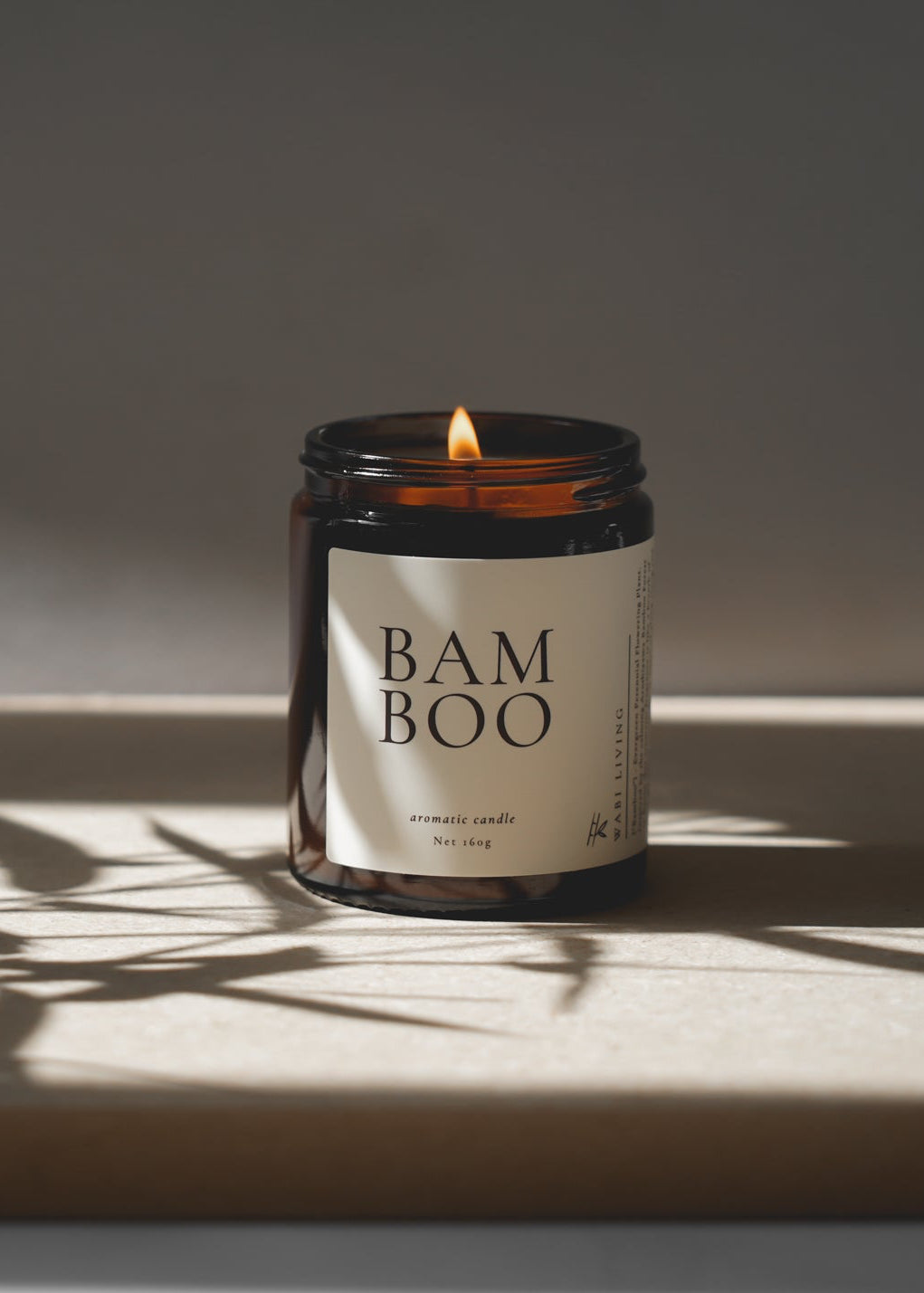 Candle labeled 'Bamboo' on a reflective surface with a soft shadow.